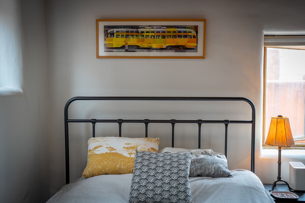 Cozy up in your thoughtfully decorated bedroom with vintage train artwork and warm golden accents welcoming you home.