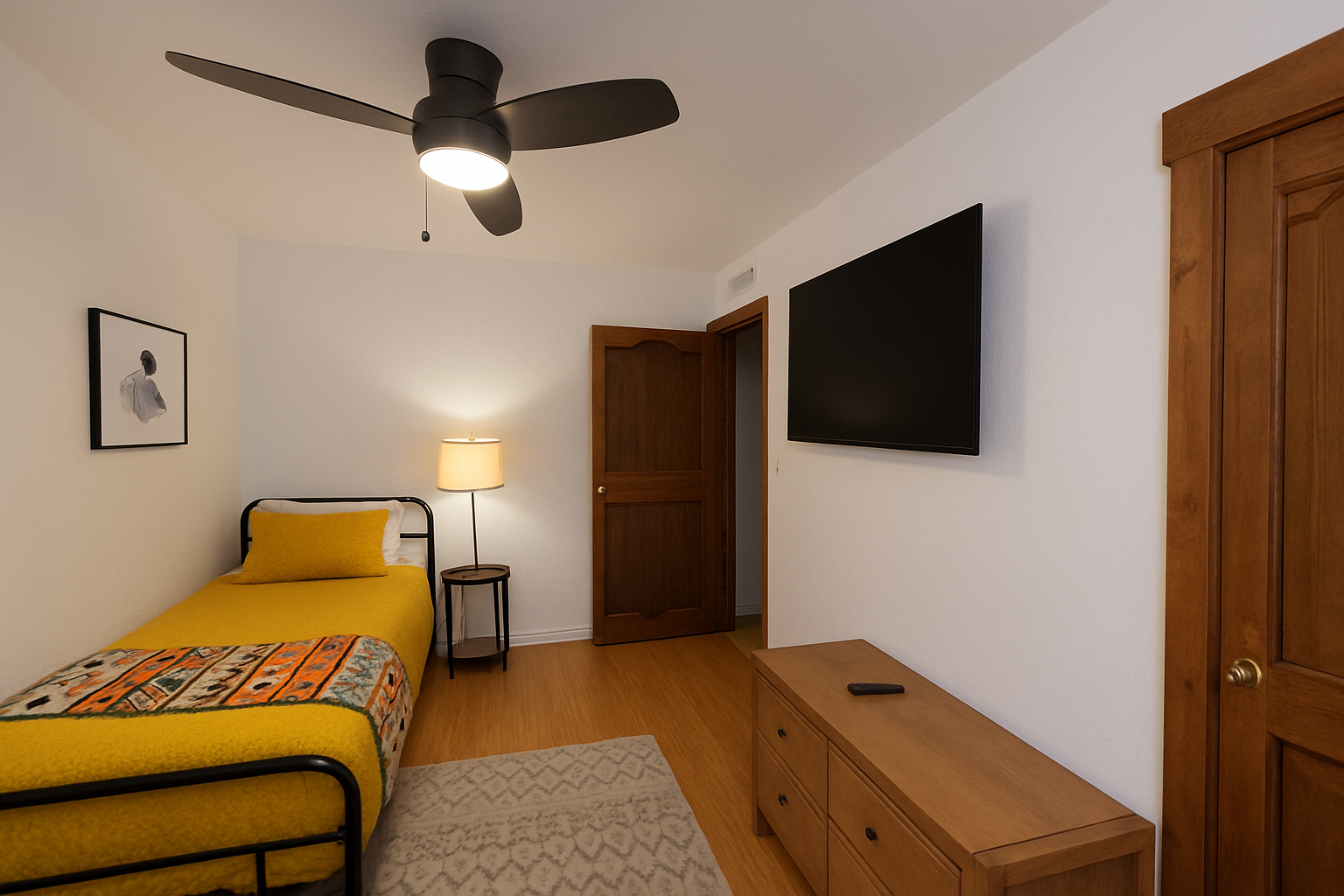 Your comfortable bedroom features a cozy single bed with vibrant yellow bedding, wall-mounted TV for entertainment, and built-in storage to keep your belongings organized during your stay.