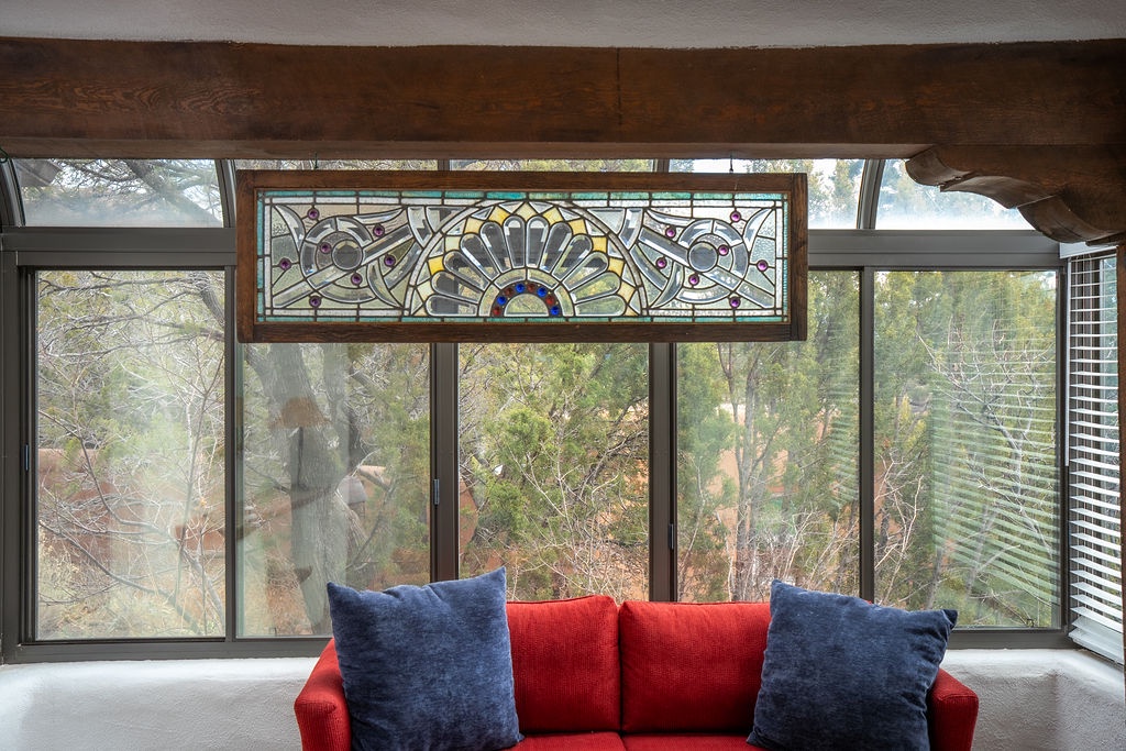 Relax on your cozy red sofa beneath stunning stained glass art, watching sunlight dance through the windows.