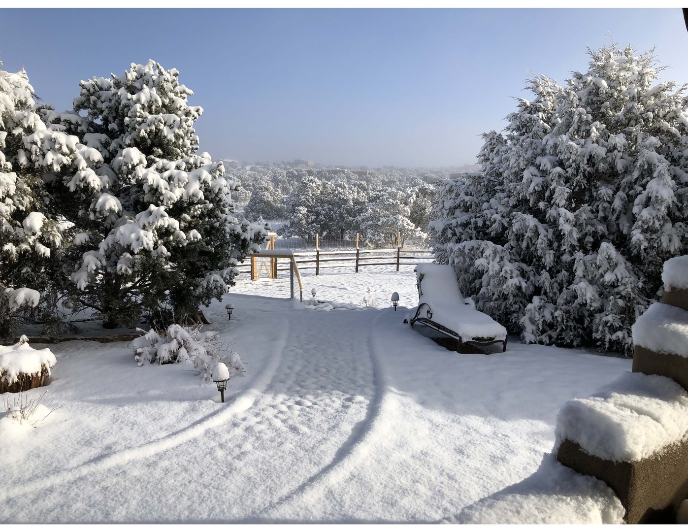 Snow-blanketed grounds frame a stunning winter vista, with evergreens dusted in fresh powder and distant mountains creating a serene seasonal backdrop at this mountain retreat.