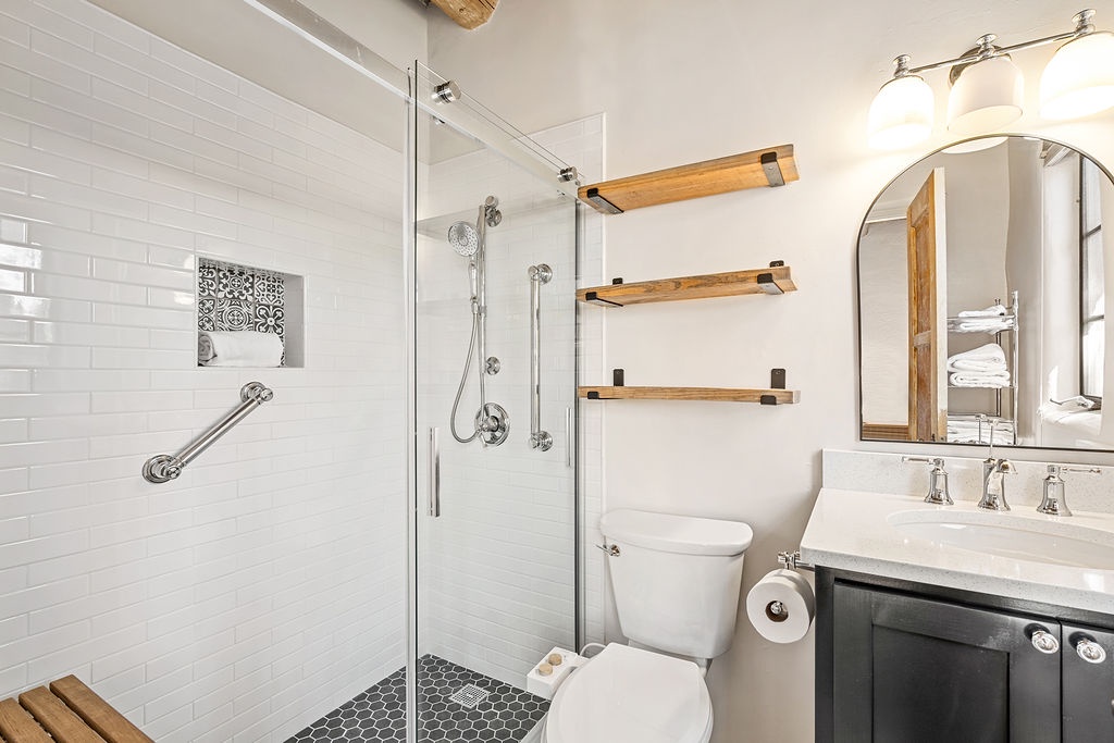 Refresh in your stylish bathroom featuring a spacious glass shower, warm wood accents, and thoughtful touches that make your daily routine feel luxurious.
