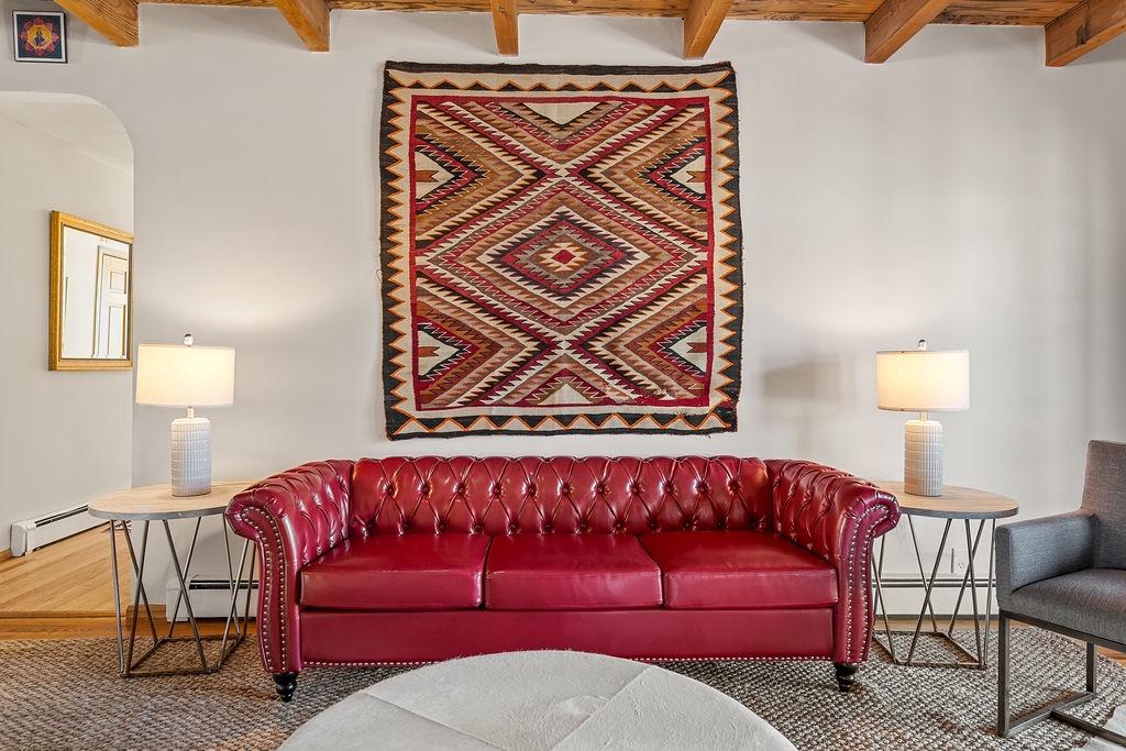 Sink into this luxurious red leather sofa beneath stunning Native American textiles and rustic wooden beams.