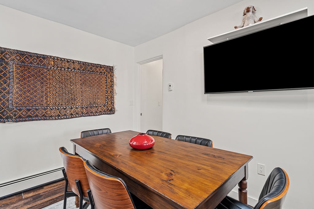 You'll love gathering around this warm wooden dining table, where meals become memories under the vibrant tapestry and large screen.