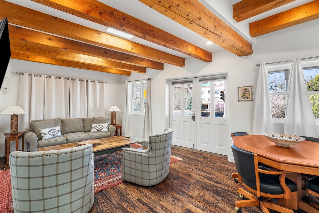 Relax under rustic wooden beams in your bright living space, where comfortable seating and warm natural light create the perfect atmosphere for memorable gatherings.