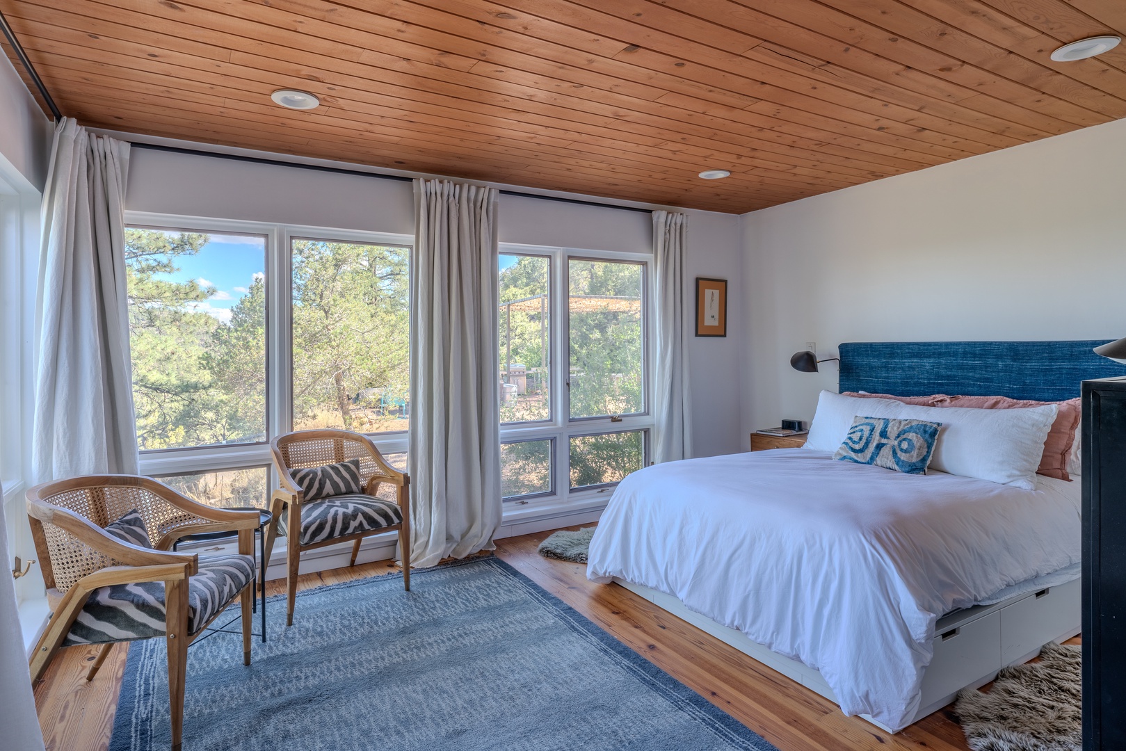 Unwind in a beautifully appointed bedroom featuring a custom-crafted headboard, original paintings, and one-of-a-kind textile art. Floor-to-ceiling windows invite in natural light and peaceful mountain views.