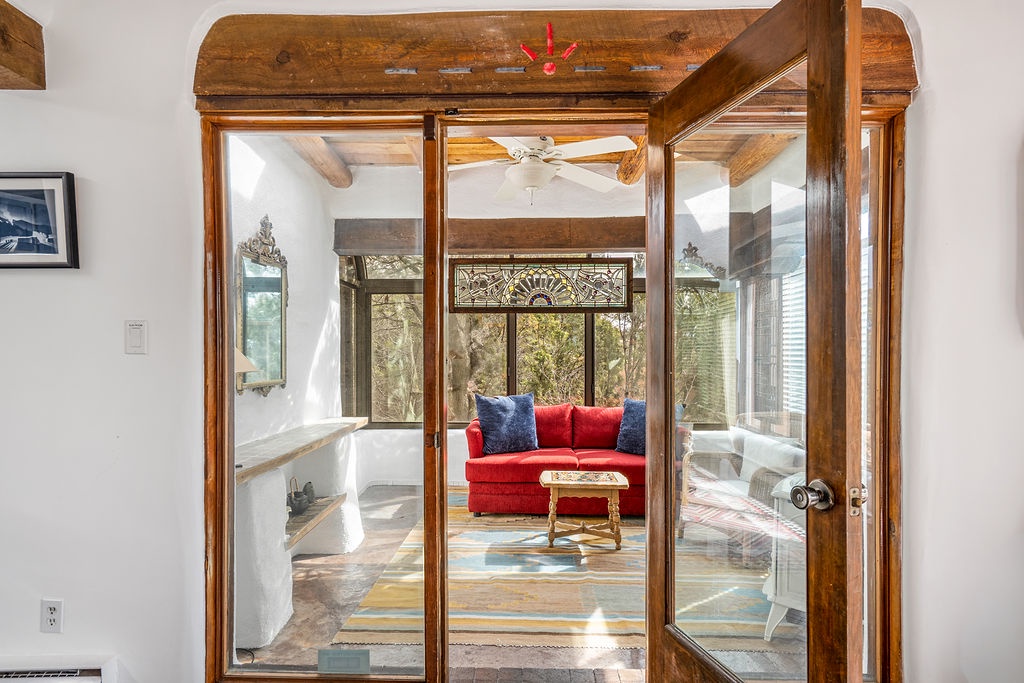 Step into your bright sunroom where rustic beams meet modern comfort—unwind on the red sofa while natural light streams through surrounding windows.