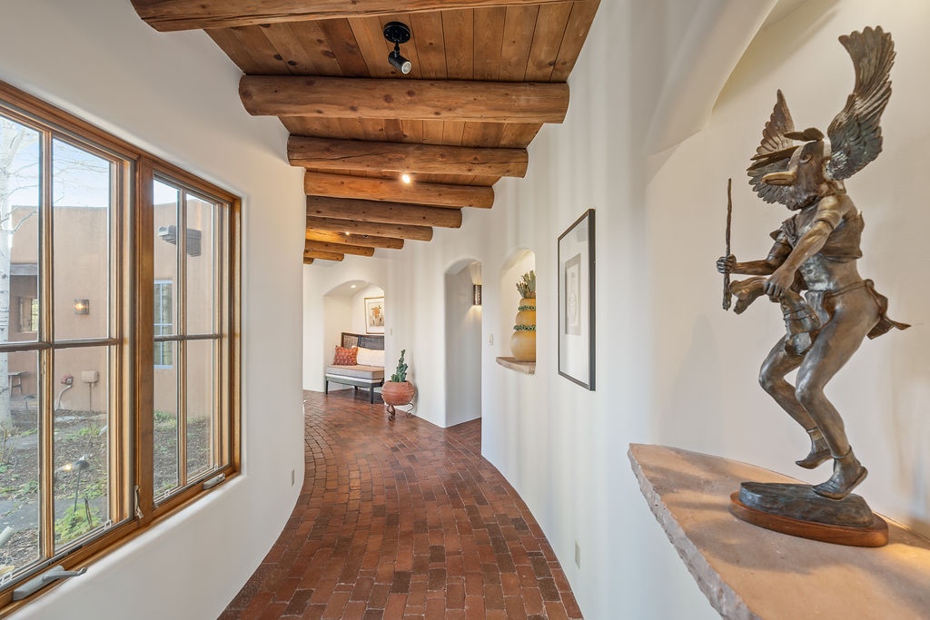 Your hallway features rustic wood beams overhead and warm brick floors beneath your feet, creating an inviting path through this thoughtfully designed space.