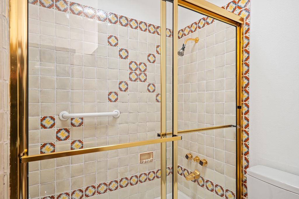 Step into your luxurious shower featuring stunning mosaic tilework and elegant gold fixtures that create a spa-like retreat.