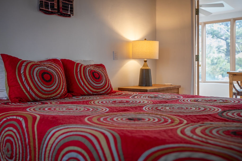 Sink into comfort with vibrant red bedding and warm lamplight creating your perfect retreat. The peaceful view adds tranquility to your stay.