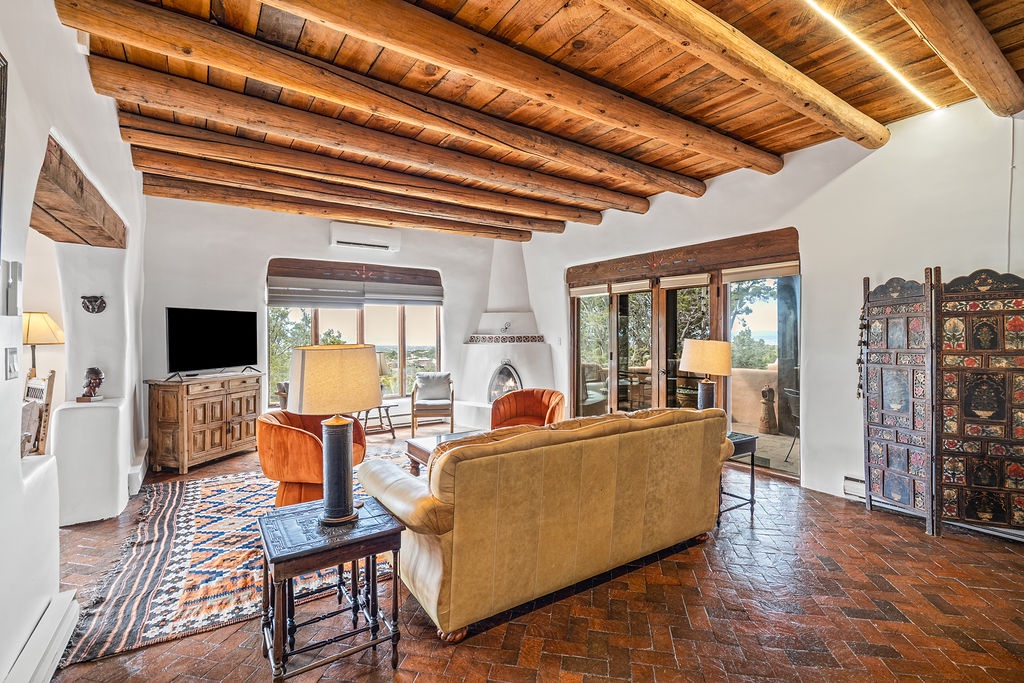 Unwind beneath authentic wooden beams in your spacious living room, where warm terracotta tiles meet rich textures and desert views.