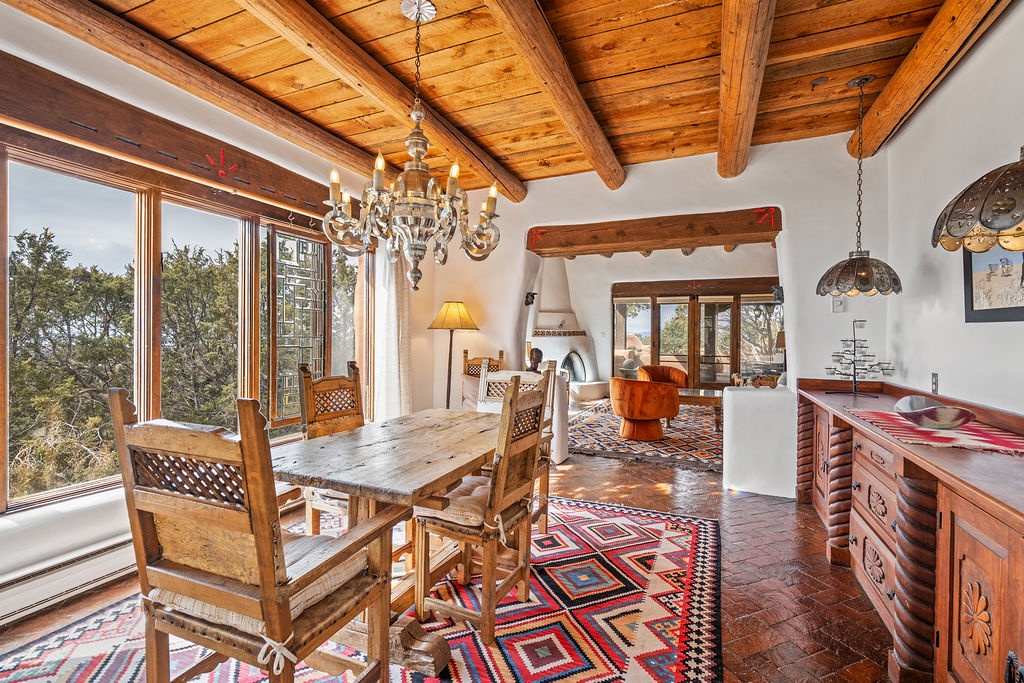 Step into your rustic dining room with exposed beams, handcrafted furniture, and stunning tree views through expansive windows.