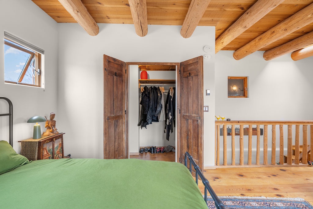 Unpack your belongings in this charming loft bedroom with rustic wood beams, built-in wardrobe, and peaceful mountain views from your window.