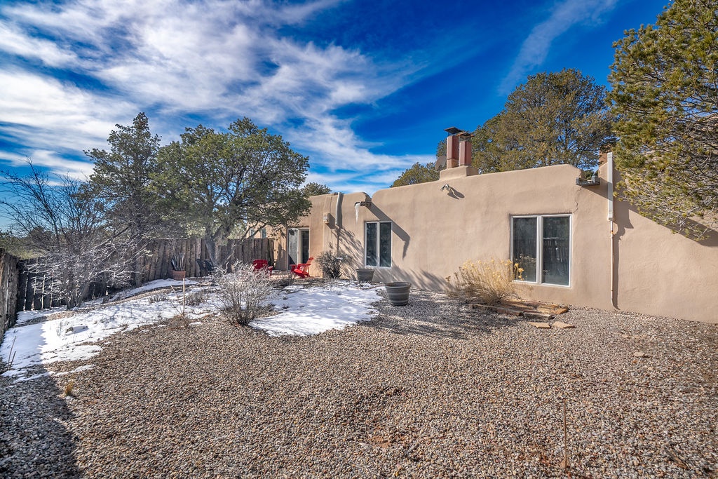 Adobe-style retreat nestled among mature trees with winter snow dusting the landscape and mountain views beyond.