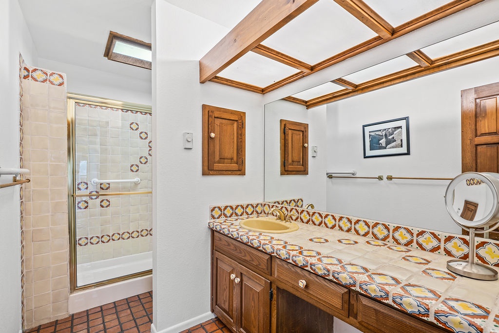 Relax in your charming bathroom featuring warm wood beams, colorful handcrafted tile, and a soothing tub perfect for unwinding.