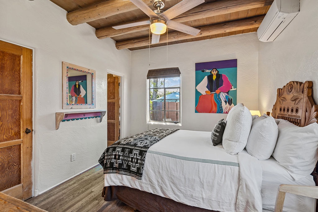 Sink into this beautifully appointed bedroom where rustic charm meets artistic flair, with exposed wooden beams overhead and vibrant local artwork adorning your walls.