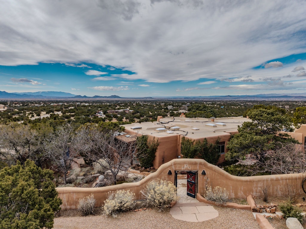 Southwestern adobe home nestled among high desert landscape with distant mountain views.