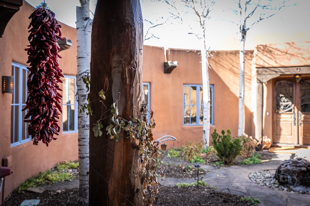 Adobe-style property showcases Southwestern charm with vibrant chile ristras, natural landscaping, and inviting architectural details.