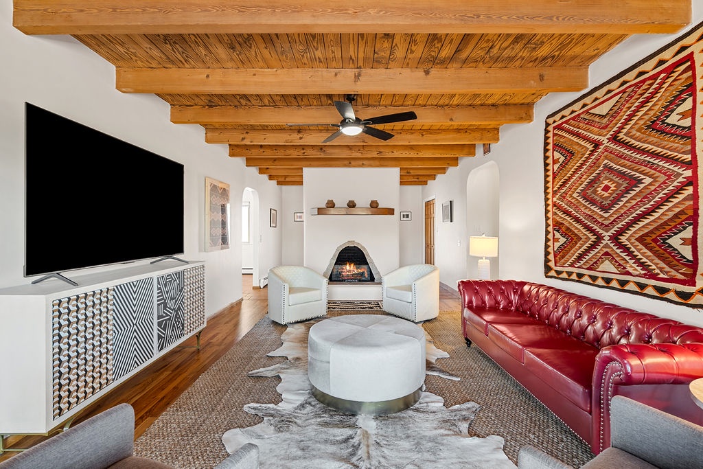 Relax in your stylish living room with exposed wood beams, cozy fireplace, and vibrant southwestern decor creating the perfect retreat atmosphere.