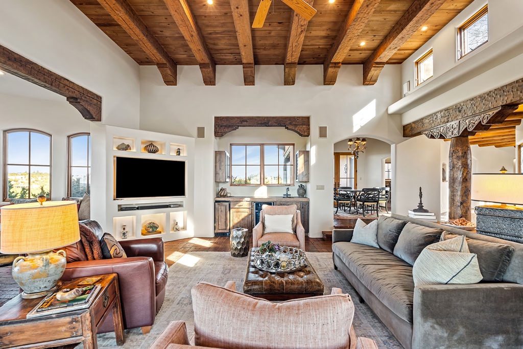 Sink into plush seating beneath stunning exposed beams while your cozy fireplace crackles and natural light streams through arched windows.