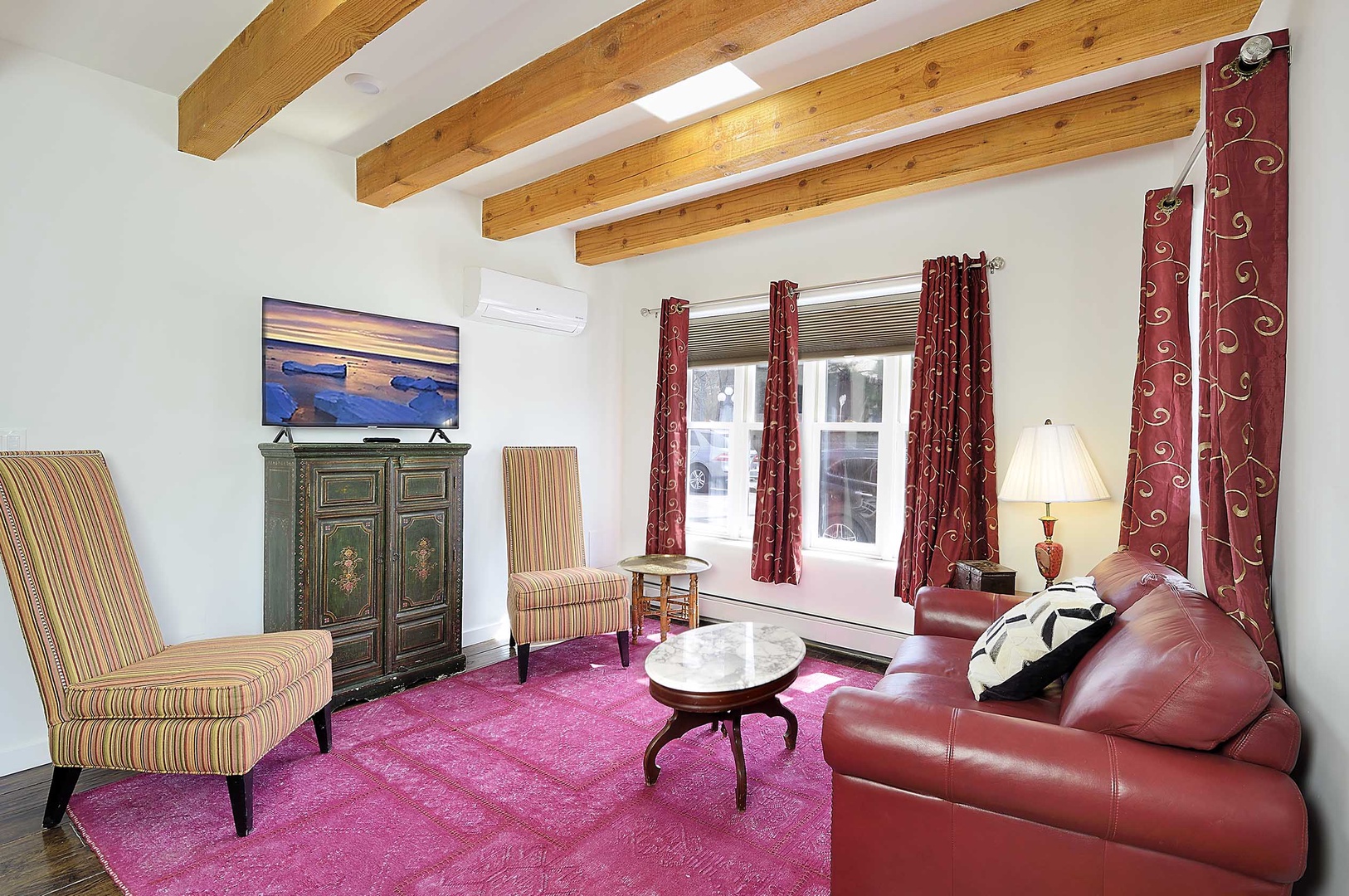 Relax under stunning exposed beams in this charming living room with plush leather seating and vibrant décor.