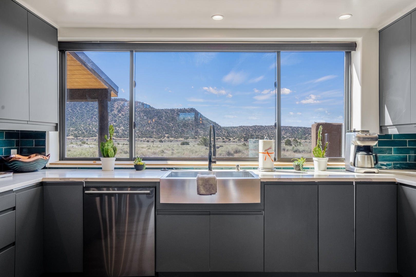 Cook with inspiration as mountains frame your culinary space through floor-to-ceiling windows in this sleek, fully-equipped kitchen.