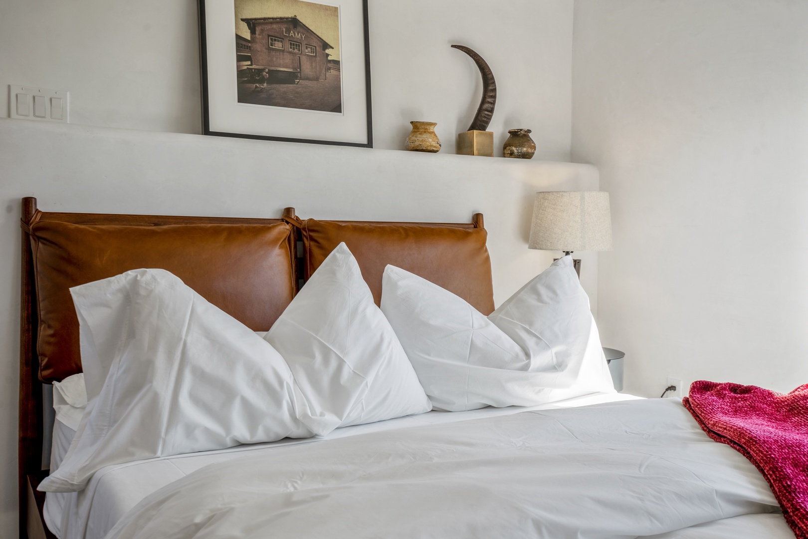 Sink into crisp white linens and plush pillows on your beautiful leather-headboard bed, surrounded by thoughtful decor.
