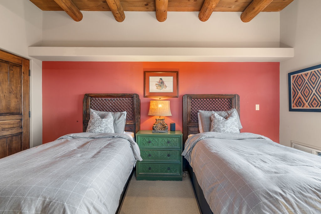 Wake up in your cozy twin bedroom with rustic wood beams overhead and vibrant Southwest-inspired decor creating a warm, artistic retreat.