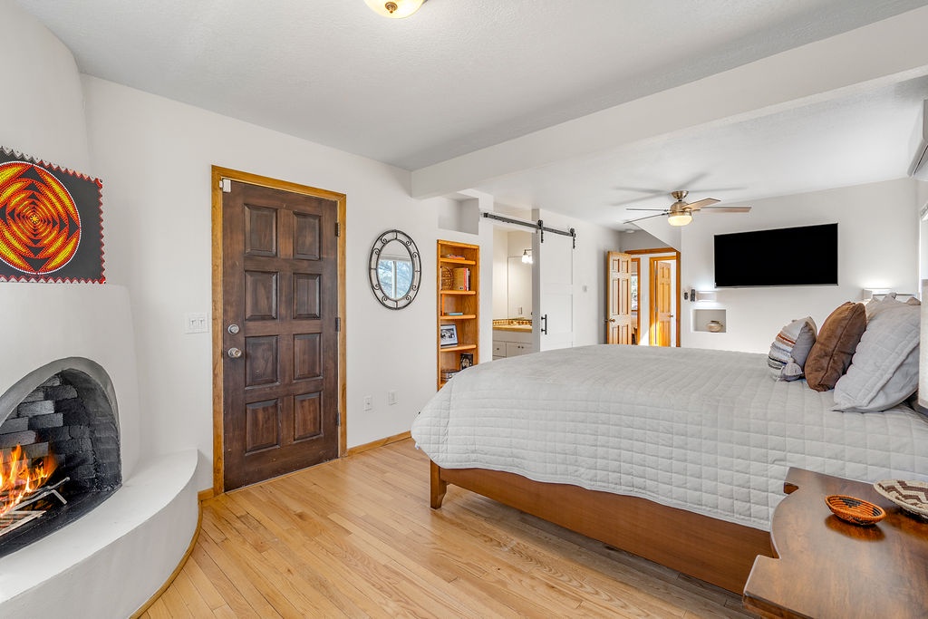 Cozy up in your spacious bedroom with crackling fireplace, plush bedding, and warm wood accents for ultimate relaxation.