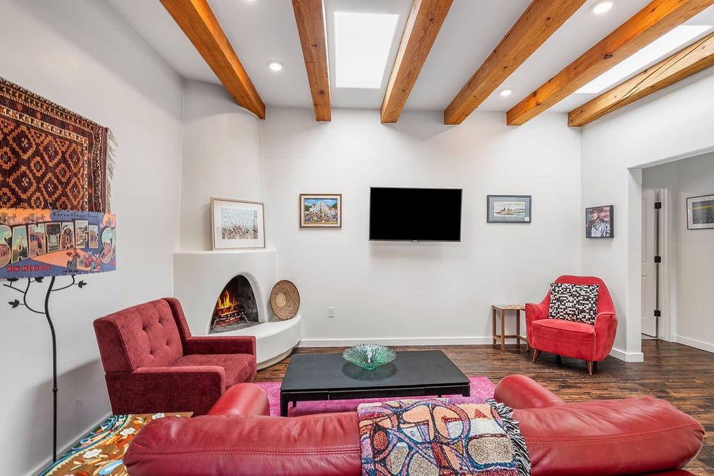 Unwind in your stylish living space featuring exposed wood beams, cozy fireplace, and vibrant artwork creating the perfect atmosphere for relaxation.