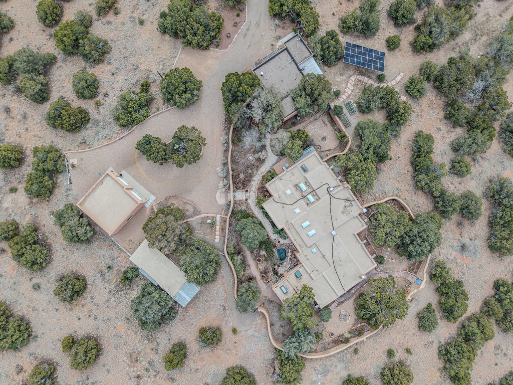 Expansive private estate nestled among mature oak trees, featuring multiple buildings, solar panels, and winding pathways through natural landscape.