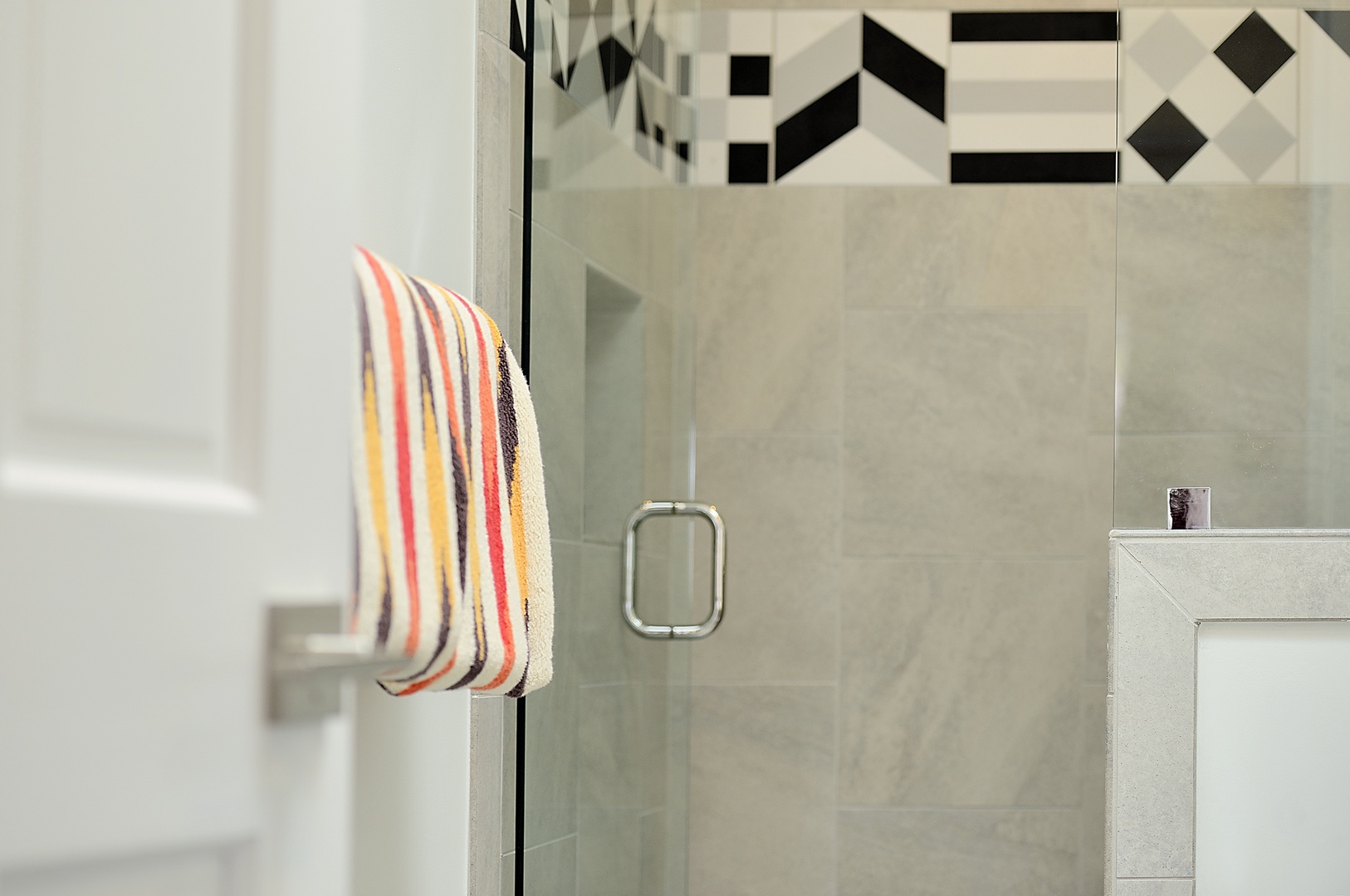 Step into your sleek glass shower with modern fixtures and stylish striped towels waiting for you.