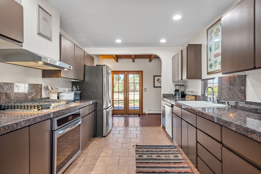 Cook meals in your fully equipped galley kitchen featuring granite countertops, stainless appliances, and warm wood cabinetry.