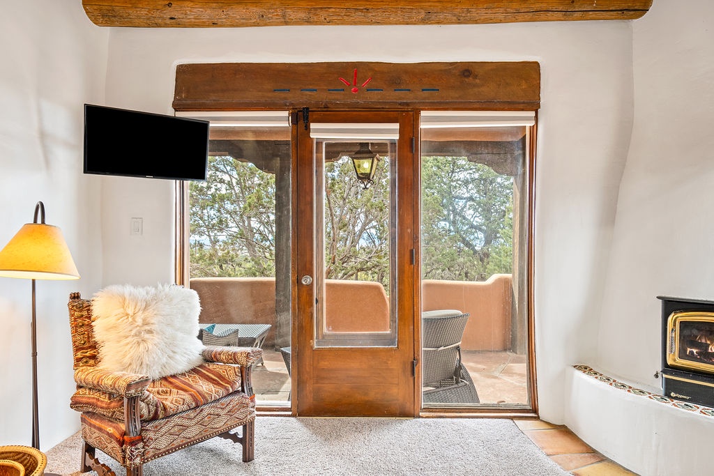Unwind in your cozy living space with warm wood beams, soft textures, and peaceful garden views through French doors.