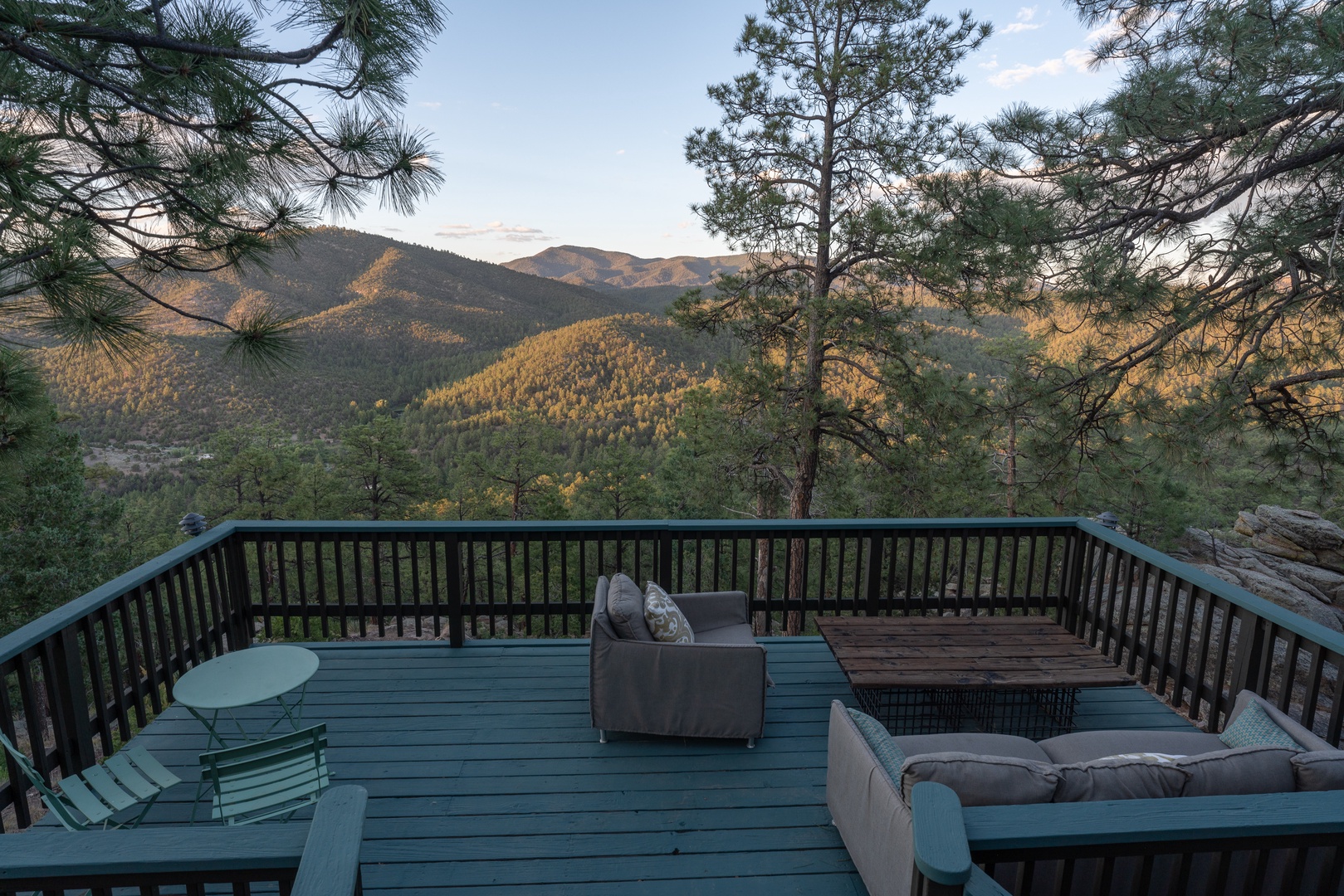 A spacious deck offering sweeping mountain vistas framed by pine trees, with comfortable seating perfect for your morning coffee or evening stargazing.