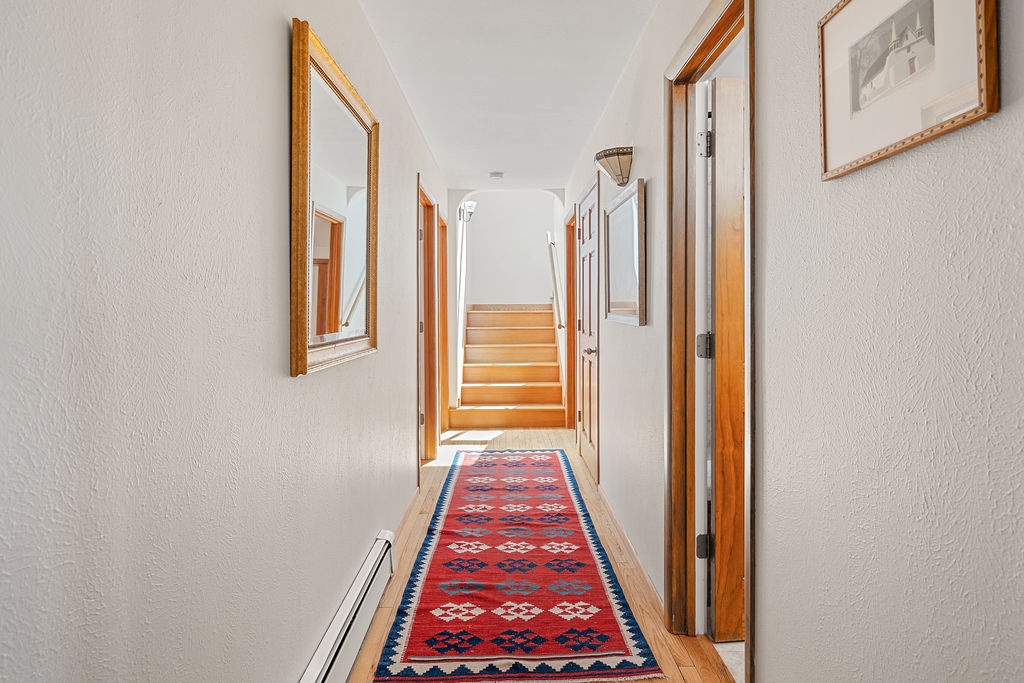 A bright hallway welcomes you with warm wood tones, beautiful artwork, and a colorful traditional rug that leads to your comfortable spaces.