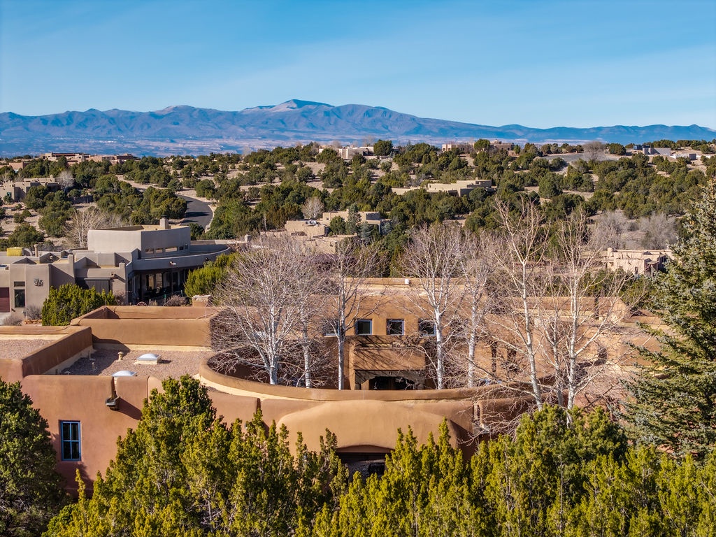 Adobe-style homes nestled in a tree-lined neighborhood with dramatic mountain backdrop.