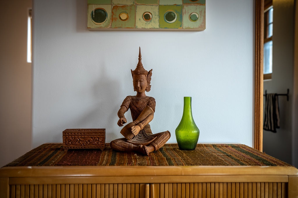 Unwind in your thoughtfully decorated space, where serene Buddha statue and vibrant green accents create a peaceful atmosphere for relaxation.