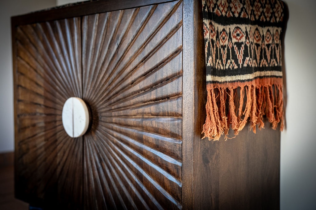 You'll love this stylish storage piece featuring beautiful sunburst woodwork and colorful woven textiles that add warmth to your space.