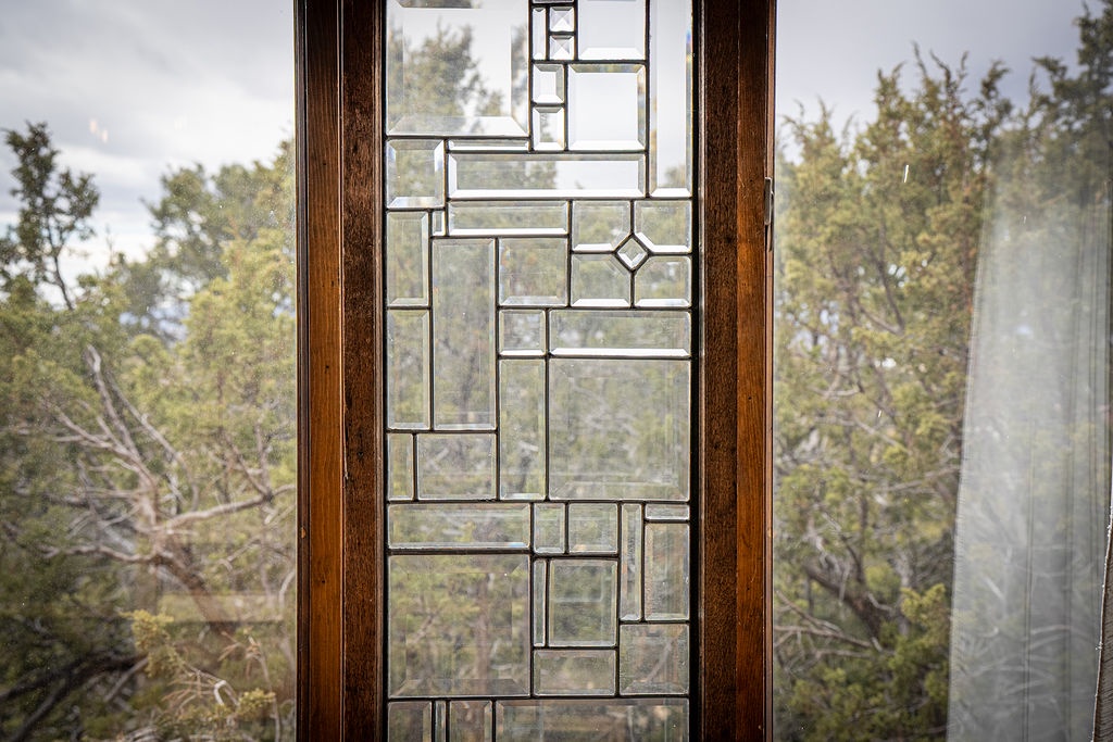 Your window frames a peaceful forest view through elegant geometric stained glass, creating beautiful patterns of natural light in your space.