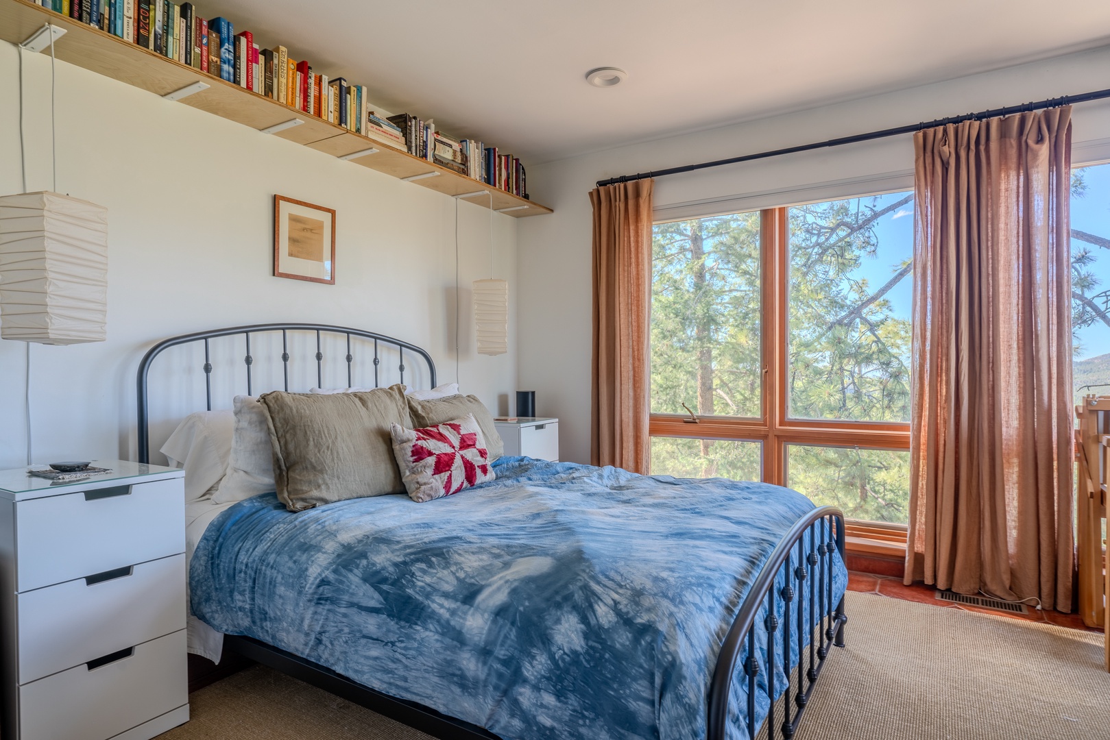 Curl up with a good book from the wall-mounted shelf, then drift off beneath soft linens as natural light fills your peaceful bedroom retreat overlooking mountain pines.