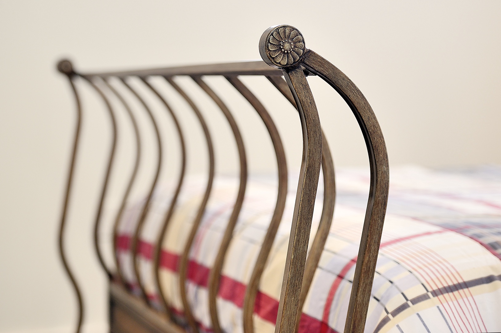 Rest easy on your elegantly crafted metal bed frame with charming decorative details and cozy plaid bedding.