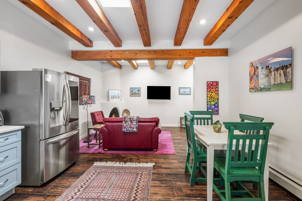 You'll love the rustic charm of exposed wooden beams overhead while enjoying your open-concept living space with modern amenities and colorful artwork.