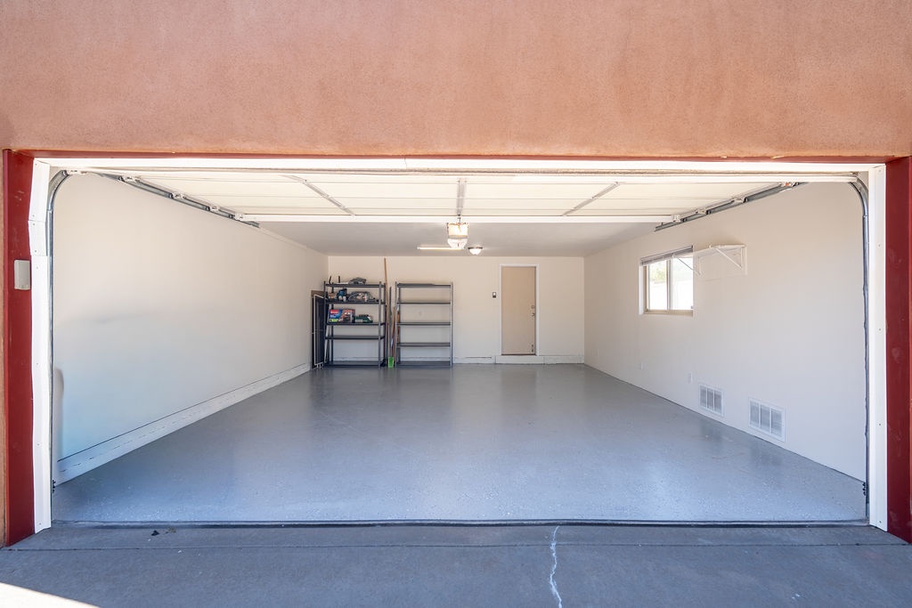 Spacious garage with clean floors, storage shelving, and overhead door access for your vehicle and belongings.