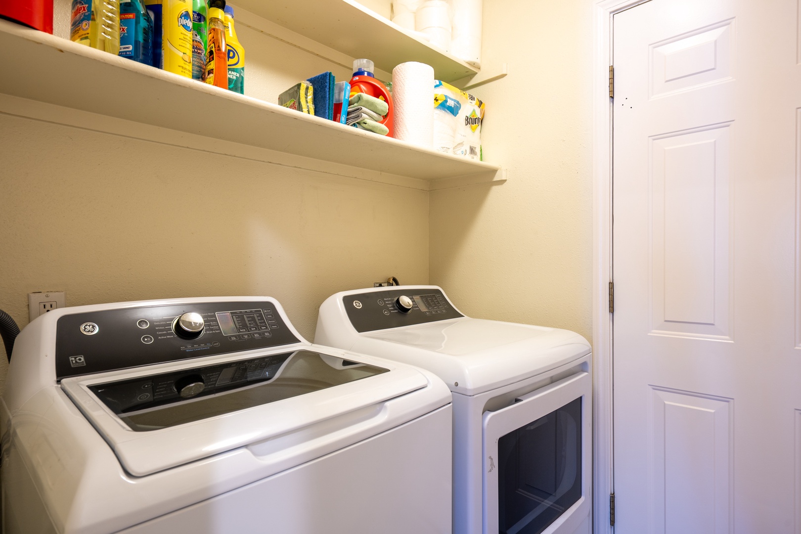 Your dedicated laundry room features a full-size washer and dryer with convenient storage shelves stocked with detergents and supplies for your convenience.