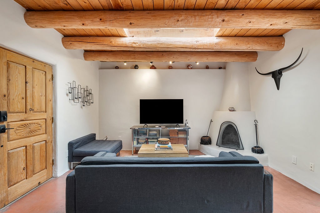 Relax in your rustic living room with exposed wooden beams, cozy fireplace, and modern amenities for the perfect mountain retreat.