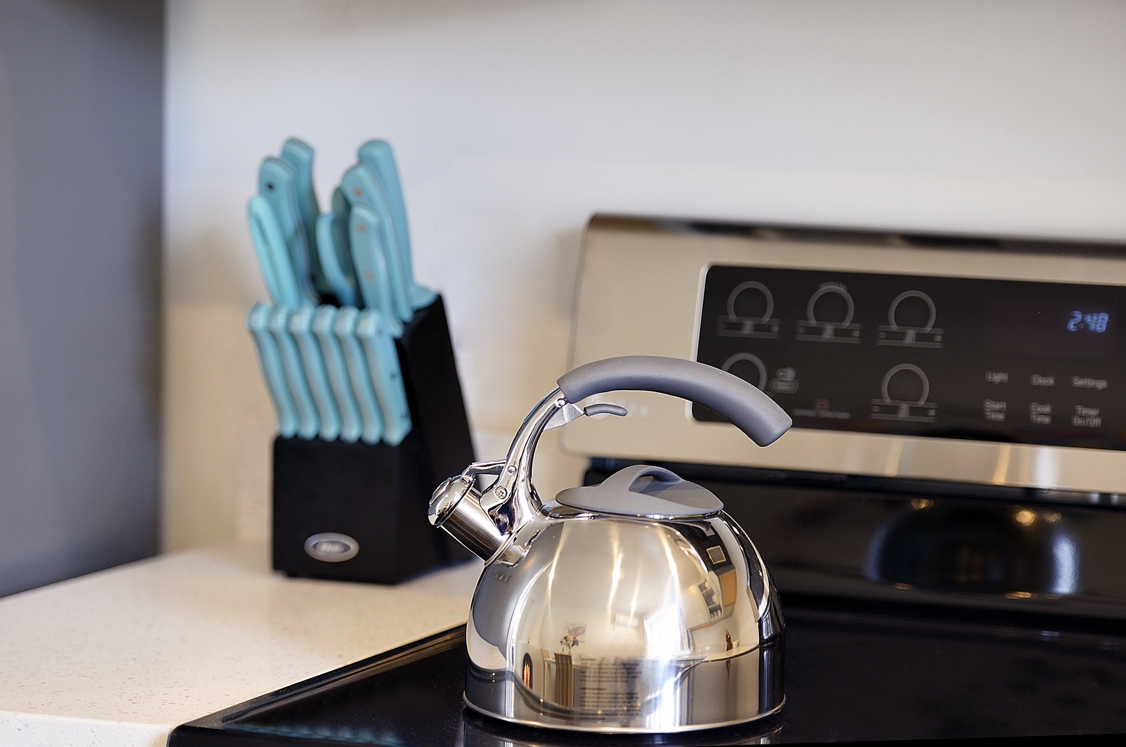 Your sleek kitchen awaits with a gleaming kettle and complete knife set, ready for your culinary adventures.
