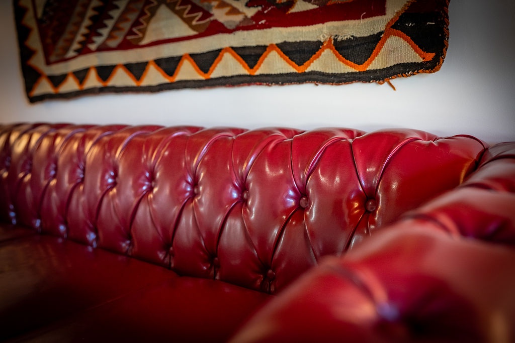 Sink into this luxurious burgundy leather sofa, perfectly paired with traditional textiles for your ultimate comfort and relaxation.