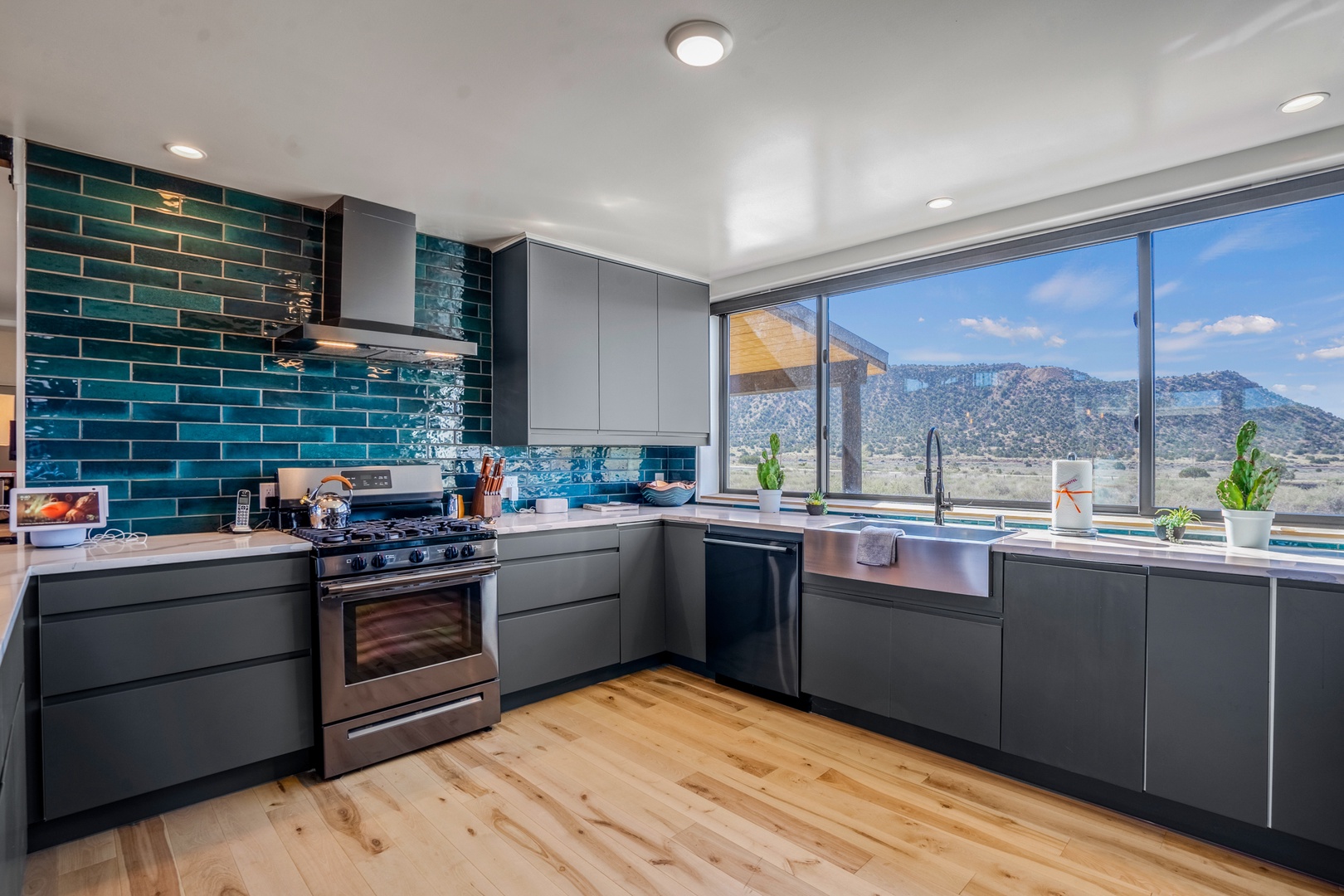 Cook with dramatic mountain views as your backdrop in this stunning modern kitchen with sleek appliances and vibrant teal tile.