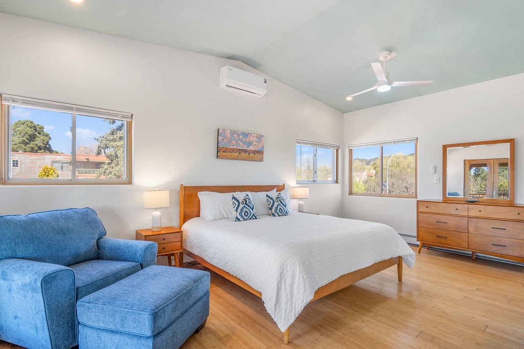 Unwind in your spacious bedroom featuring crisp linens, a cozy reading chair, and windows framing leafy neighborhood views.