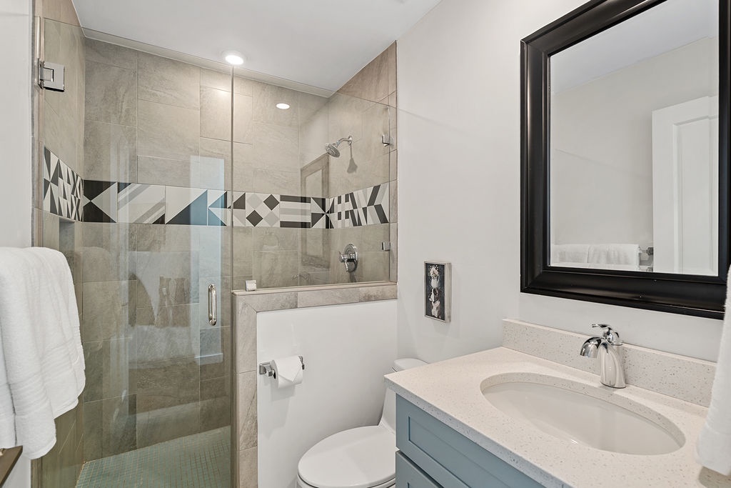 Unwind in your modern bathroom featuring a spacious walk-in shower with striking geometric tile accents and elegant vanity.